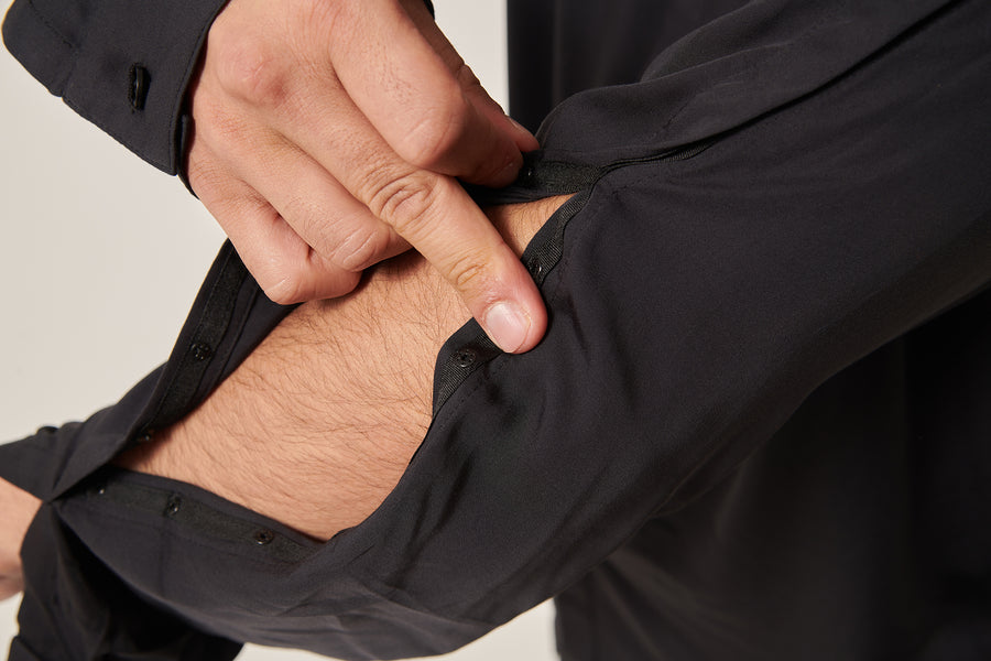 Close up of  a black bamboo silk shirt. There are poppers that fasten the sleeve opening.