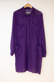 Purple chiffon long line shirt with 2 chest pockets and 2 pockets at hip height. Long sleeves. Concealed front fastening has popper tape and the sleeves. On a wooden hanger against a white back ground.
